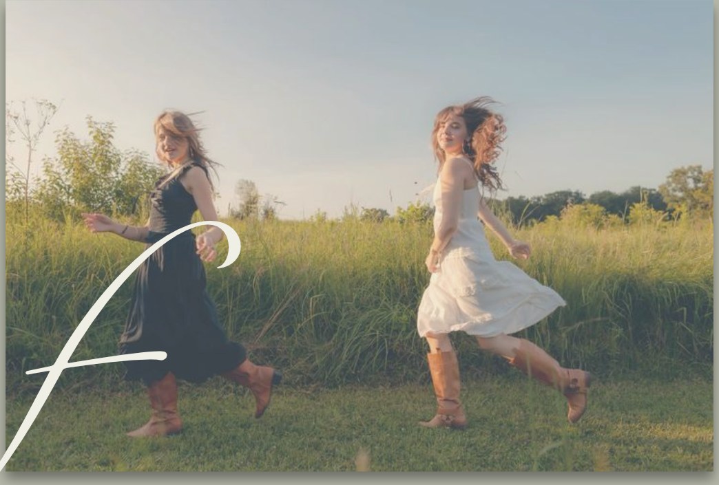 Two friends running through a summer meadow in cowboy boots
