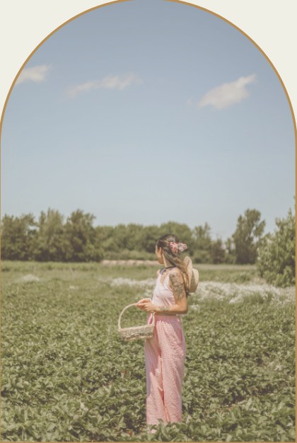 A girl in a pink dress carrying a basket through a flowering field