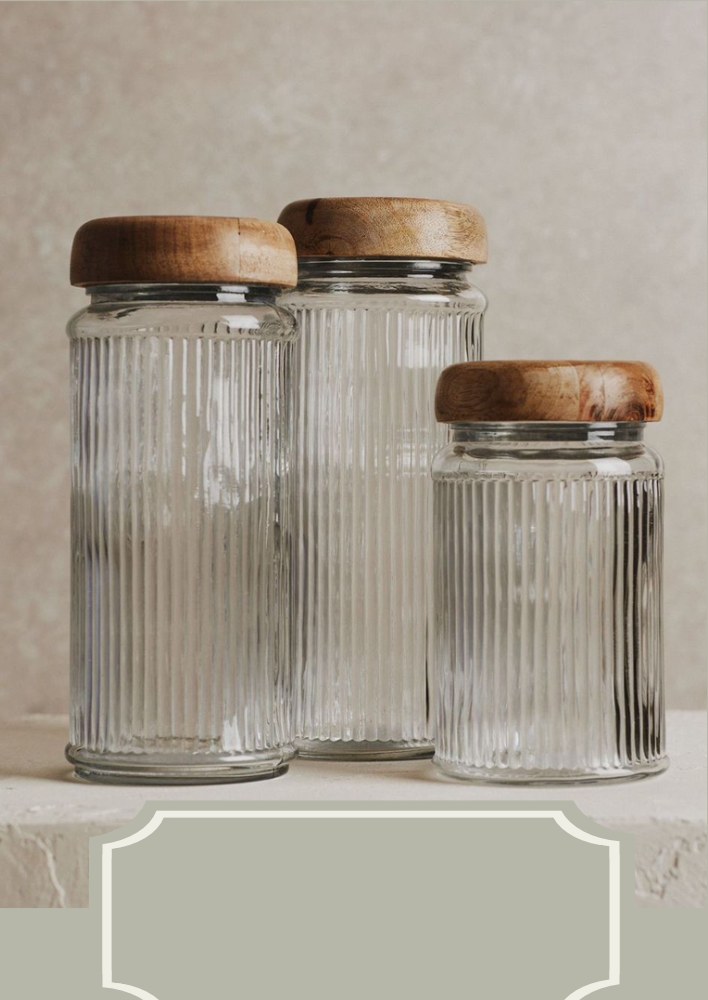Three ribbed glass storage jars with wooden lids on a stone ledge